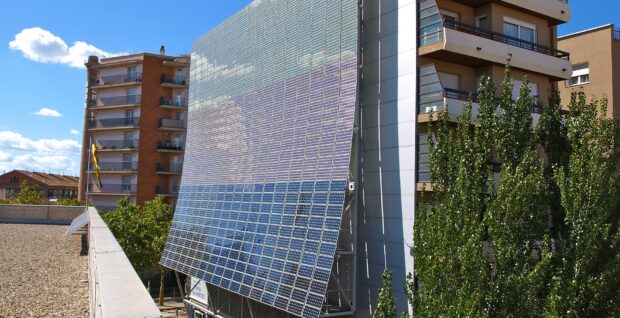 Gran instalacion fotovoltaica montada en la fachada de un edificio, con bloques de viviendas a ambos lados